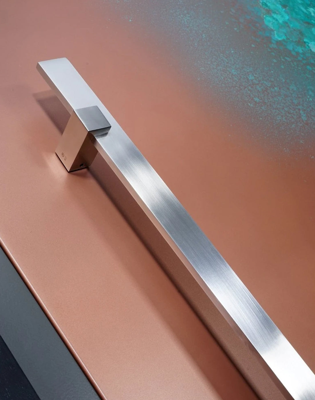 Stainless steel pull handle on a front door with a copper effect surface