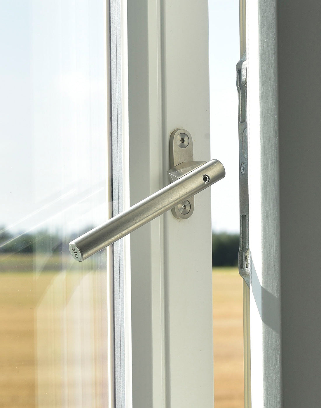 Close-up of a stainless steel window handle on a window with a blurred outdoor background