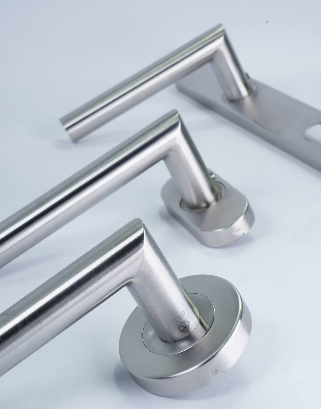 Close-up of stainless steel lever door handles from Coastal's BLU range on a white background