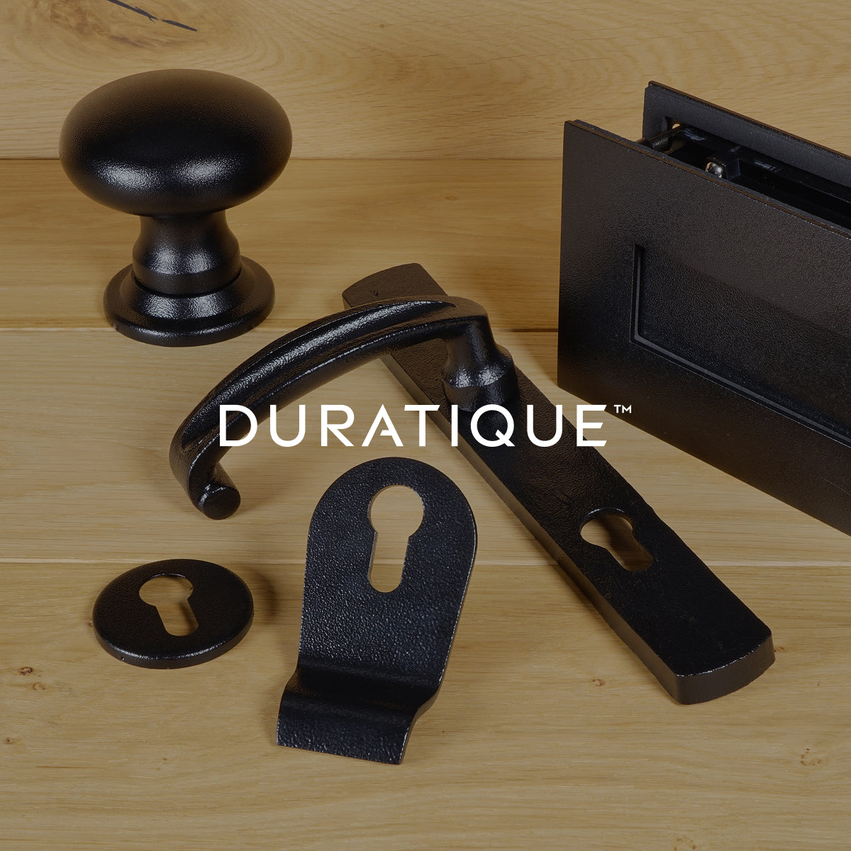 Black antique door furniture on a wooden surface, featuring the DURATIQUE brand.