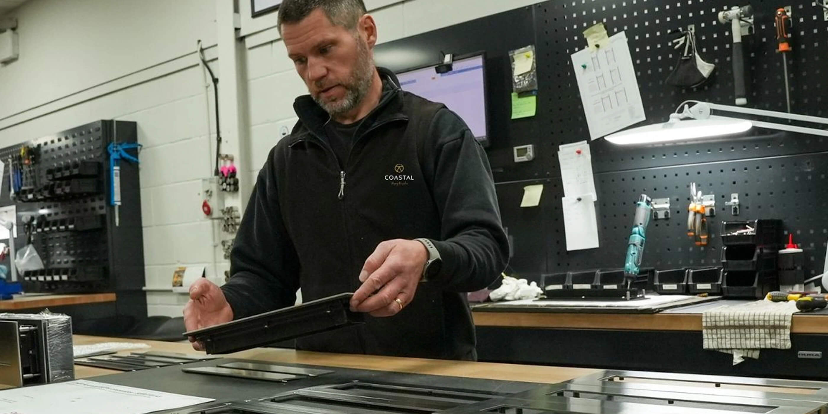 Person in a Coastal Group workshop working on a stainless steel letter plate